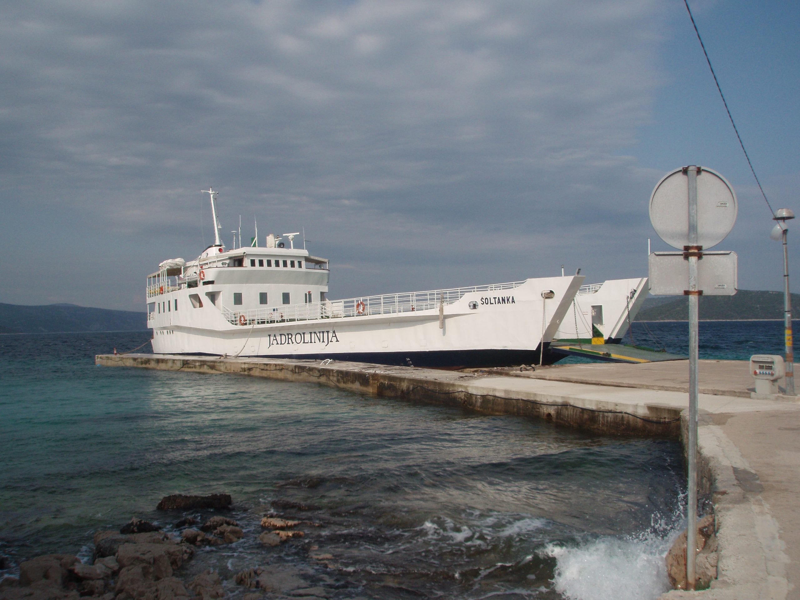 Šoltanka ferry at the dock on Drvenik Mali. On a Monday in May, the ferry carried Croatian vacationers, retired people, construction workers, and the priest from Trogir, who was rehearsing his sermon leaning over the railings, book in hands, reading out to the waves. He was the first to jump off the ferry, hurrying toward the nearby church as the ship was leaving the island in an hour, and he had to be on it.