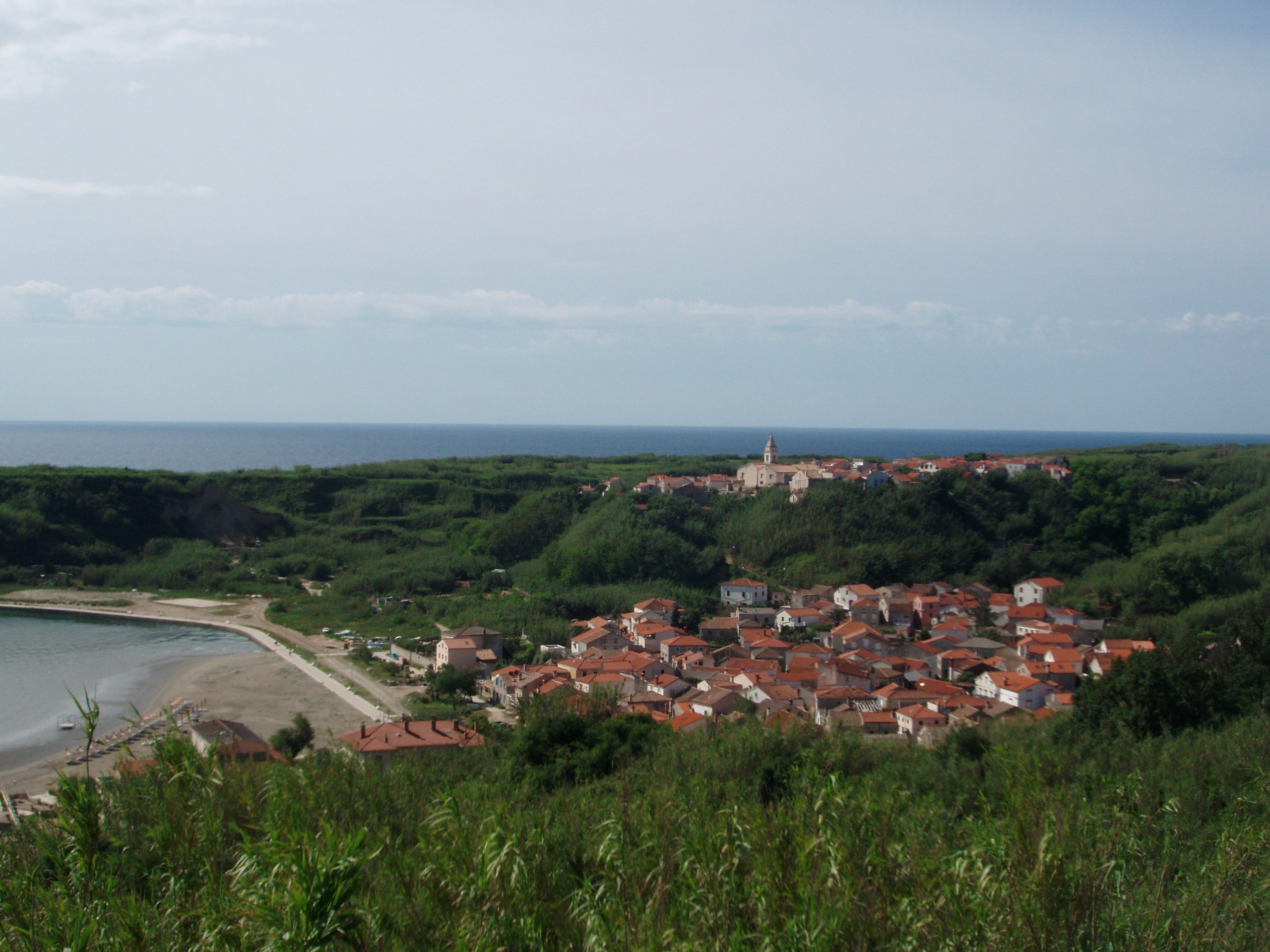 The upper and lower village of Susak, the island made of reed and sand, as seen from the path that leads toward the Susak Lighthouse. The lighthouse was built in 1881, and has been run by the same family for over thirty years now. They tend to the light, their garden, and their cats.